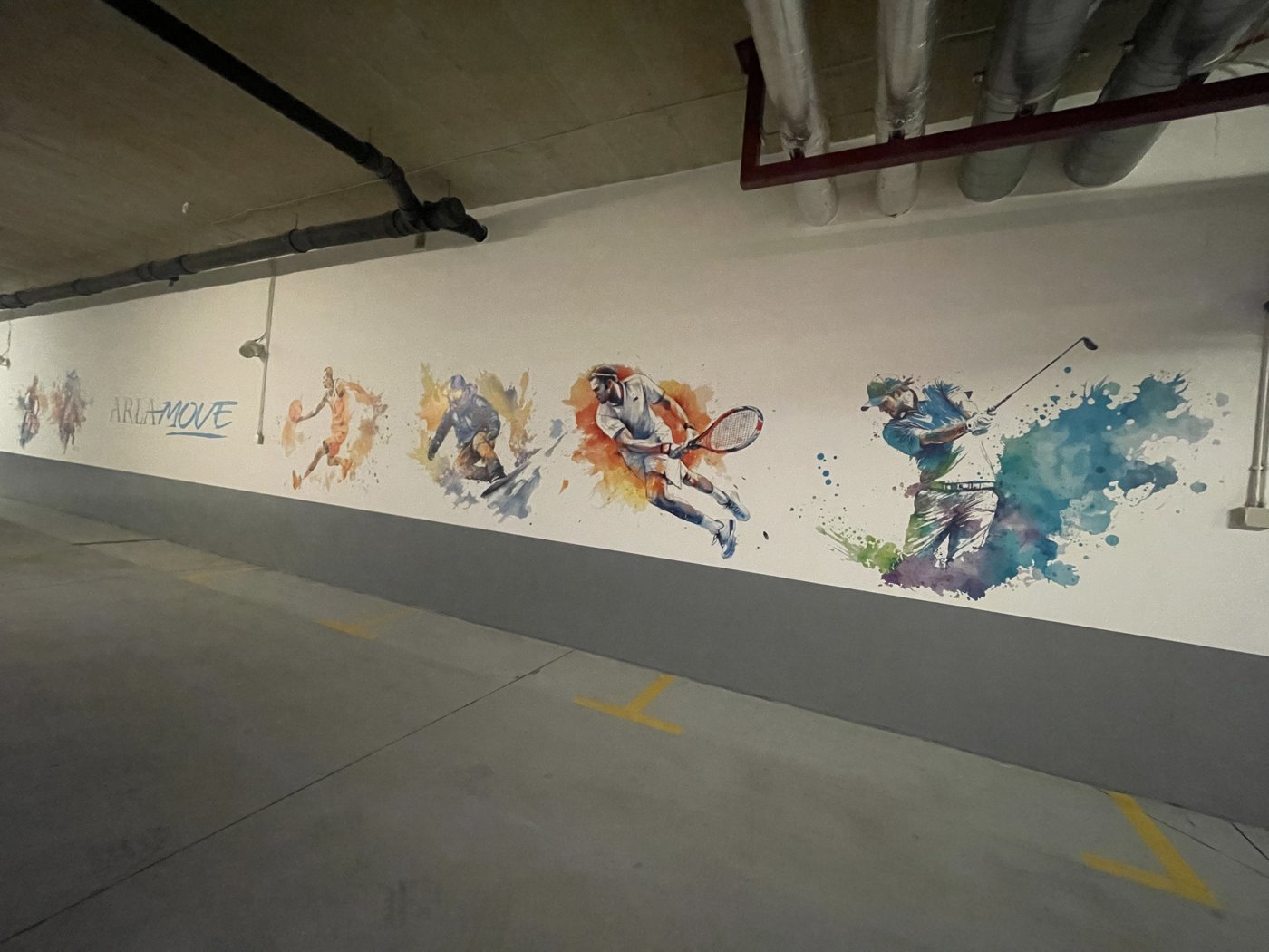 Parking podziemny w Arłamowie, sylwetki sportowców i logo ARŁAMOVE na ścianie
